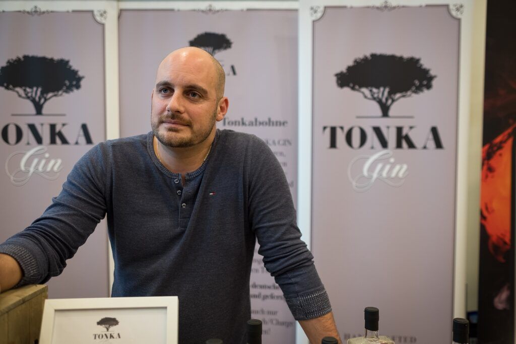 Ein kahlköpfiger Mann steht vor einer Auslage mit Tonka-Gin.